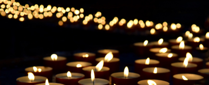 Dozens Of Lit Candles Glowing In Darkness